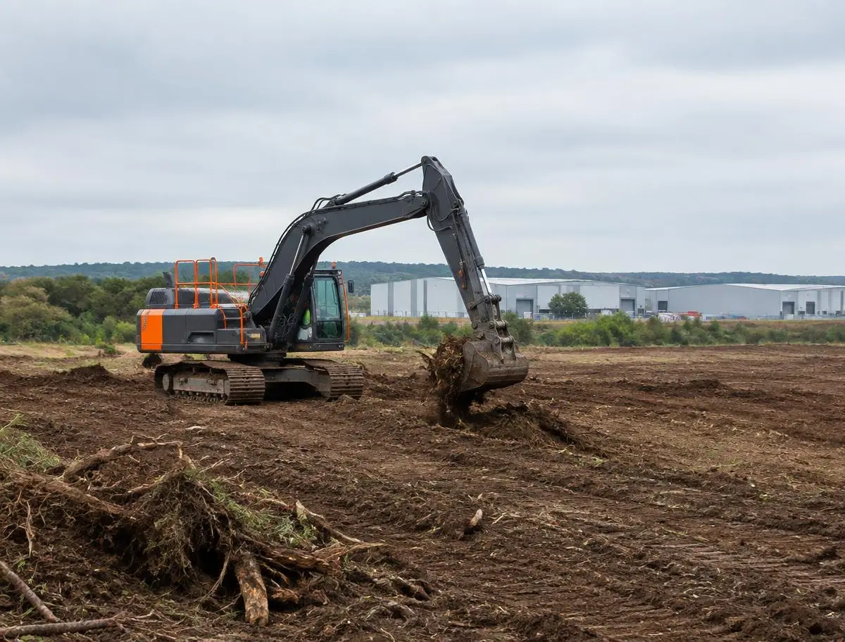 Tracked excavator clearing a large commercial development plot